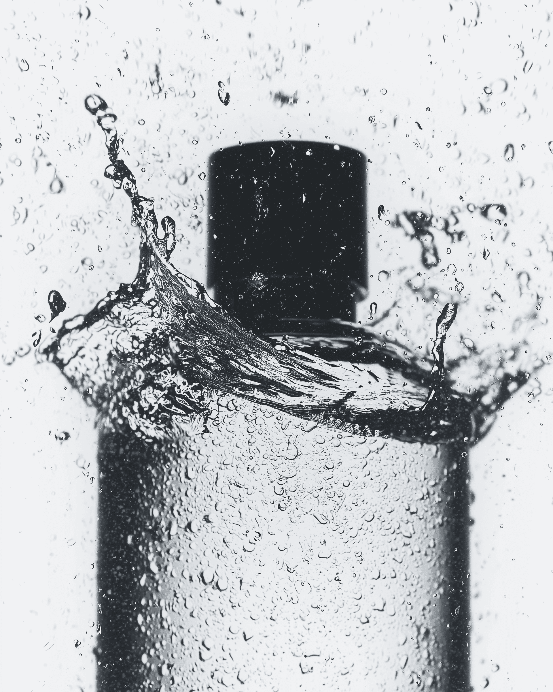 Black-capped cosmetic bottle with water splash